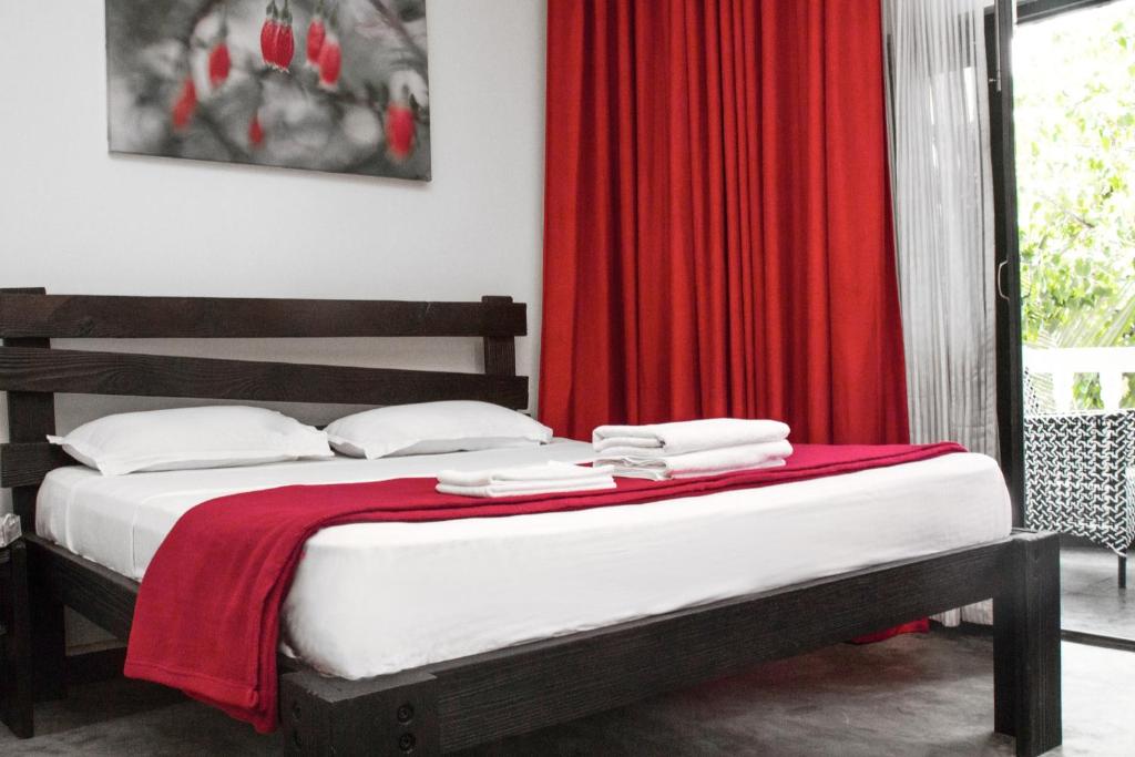 a bedroom with a bed with a red curtain at Double V Arambol in Arambol