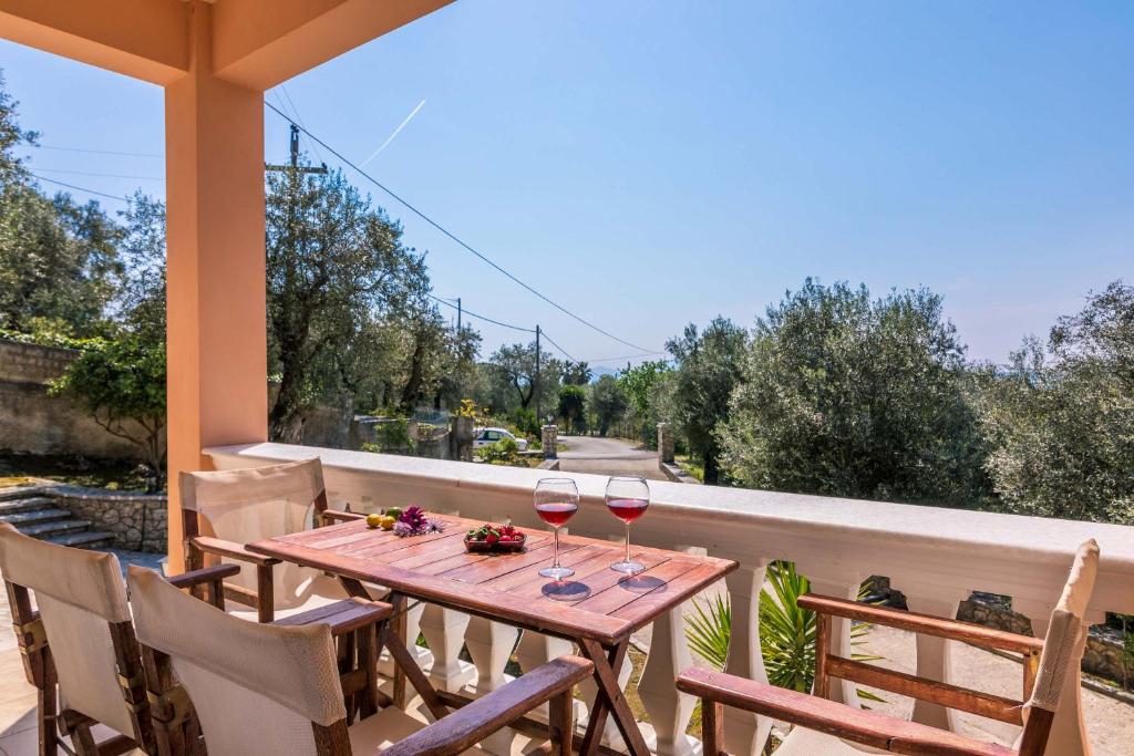 a wooden table with two glasses of wine on a balcony at The Olive Grove Cottage by Konnect - 2,5km from Ipsos in Ýpsos