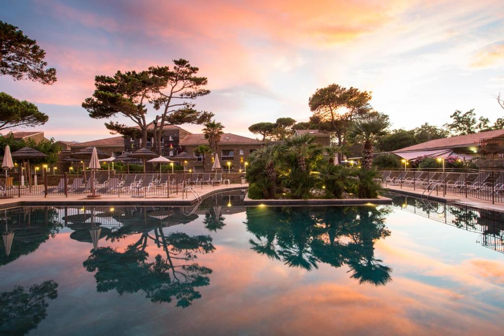 een zwembad bij zonsondergang in het resort bij Hôtel La Lagune in Lucciana