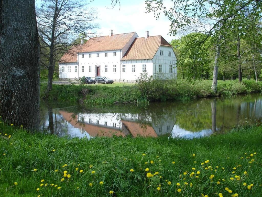 un grand bâtiment blanc à côté d'une étendue d'eau dans l'établissement Lerbæk Hovedgaard, à Frederikshavn