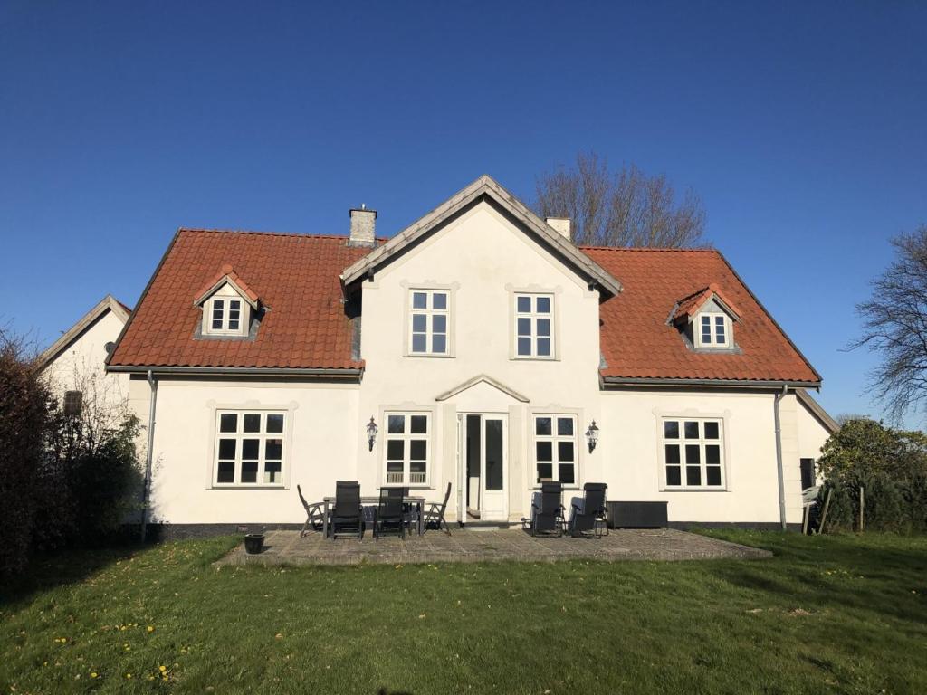 a white house with chairs and tables in a yard at Kildegaarden in Kokkedal