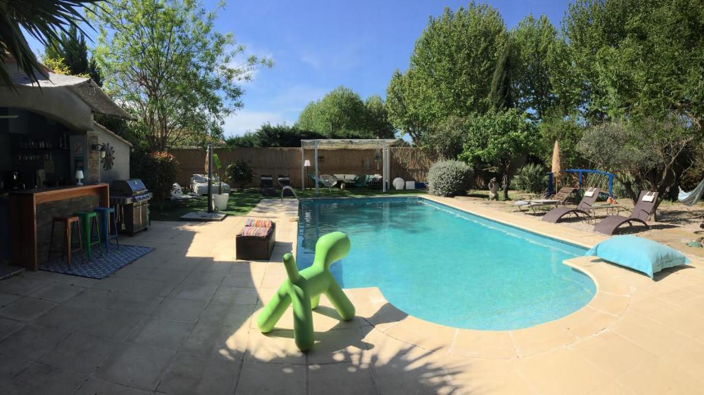 uma piscina com um escorrega verde num quintal em Villa Kalimera em Sérignan
