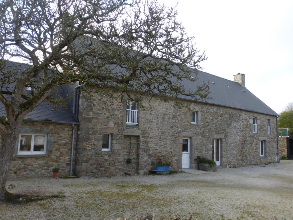 un viejo edificio de piedra con un árbol delante de él en Gîte du Lieu Piquot, en Gréville-Hague