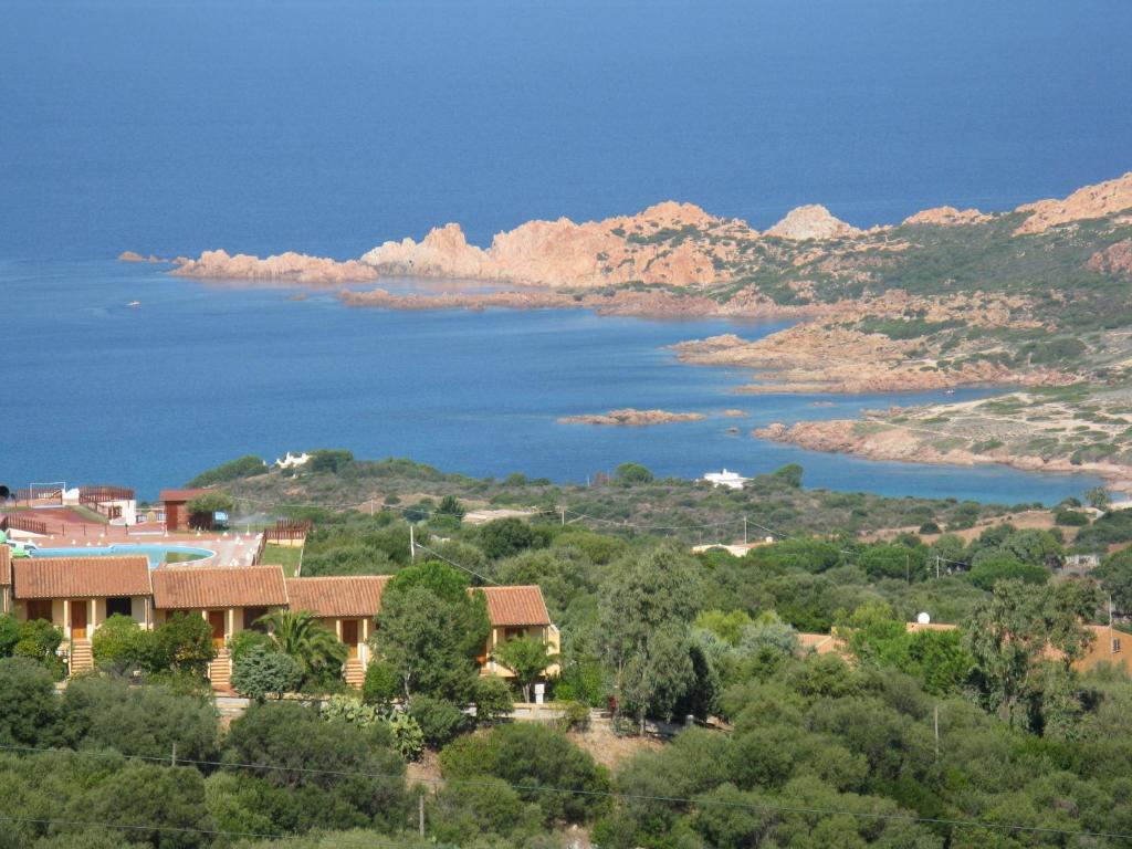 a house on a hill next to a body of water at Le Colline di Isola Rossa in Trinità d'Agultu e Vignola