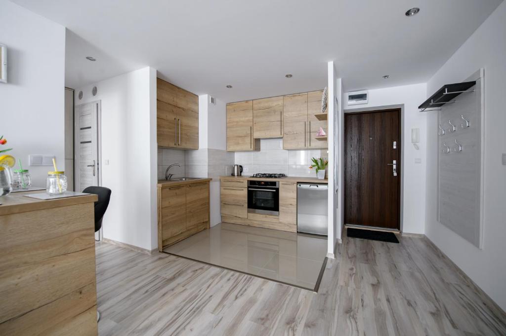 cocina con paredes blancas y armarios de madera en APARTAMENT PRZYTULNY, en Kielce