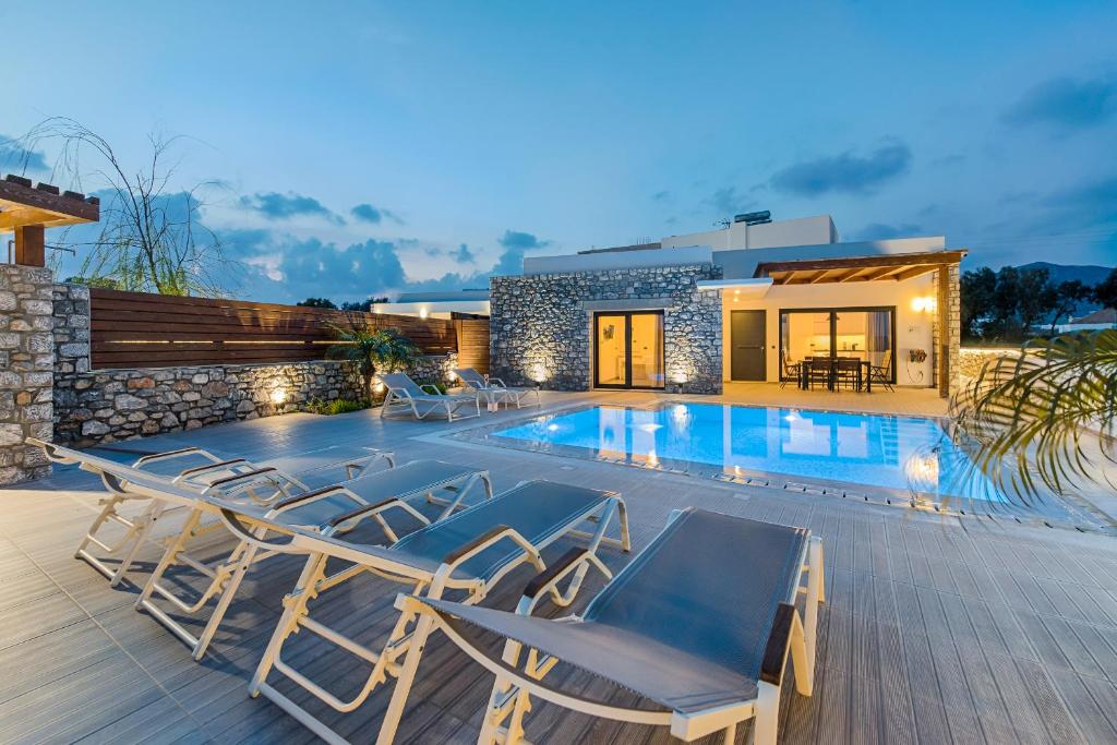a villa with a swimming pool and lounge chairs at Prasonisi Villas in Kattavía