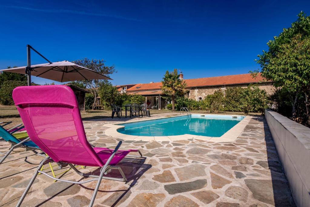 a pink chair and an umbrella next to a swimming pool at Gite Au Chant des Vents in Thurageau