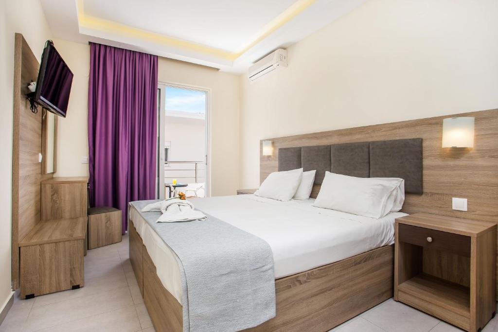 a bedroom with a large bed and a purple curtain at Patricia Studios in Faliraki
