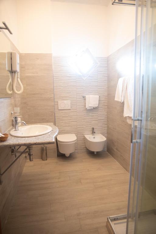 a bathroom with two sinks and a toilet and a shower at Hotel Royal in Coccorino
