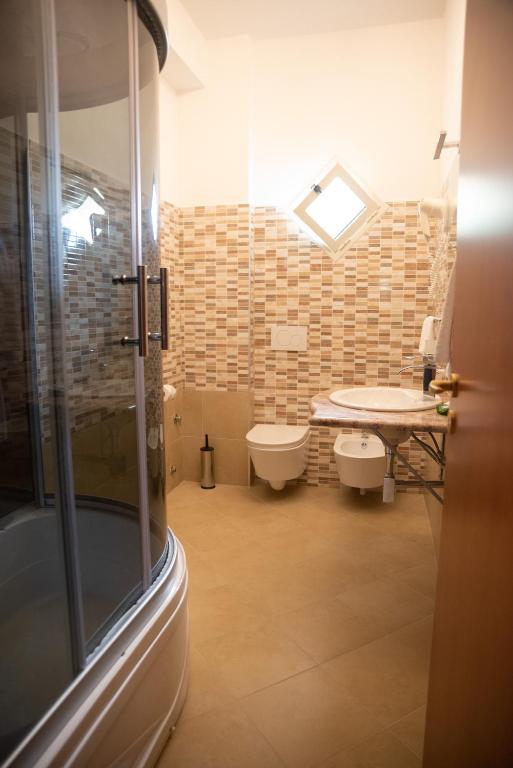 a bathroom with a sink and a toilet and a table at Hotel Royal in Coccorino
