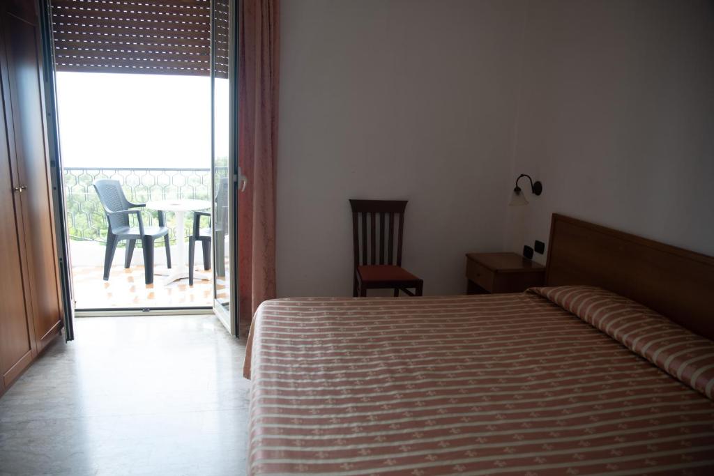 a bedroom with a bed and a balcony with a table at Hotel Royal in Coccorino