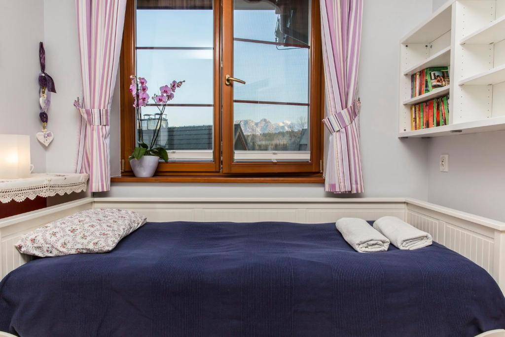 sypialnia z niebieskim łóżkiem i oknem w obiekcie Apartment Tiffany w mieście Nowe Bystre