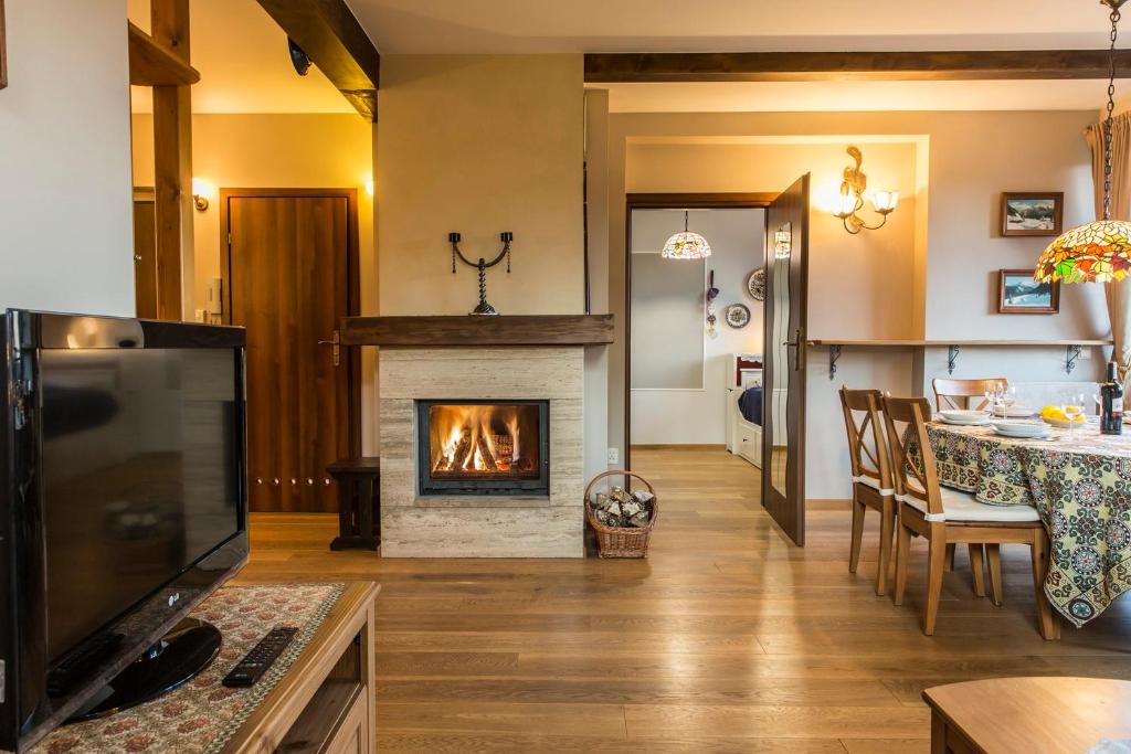 salon z kominkiem i stołem z krzesłami w obiekcie Apartment Tiffany w mieście Nowe Bystre
