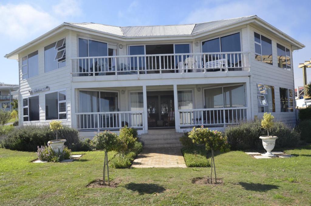 a white house with a porch and a balcony at Sitterus in Stilbaai