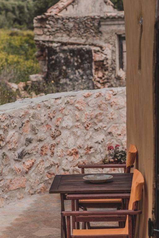a wooden table and chairs in front of a stone wall at La Casa Di Nonna in Koríthion