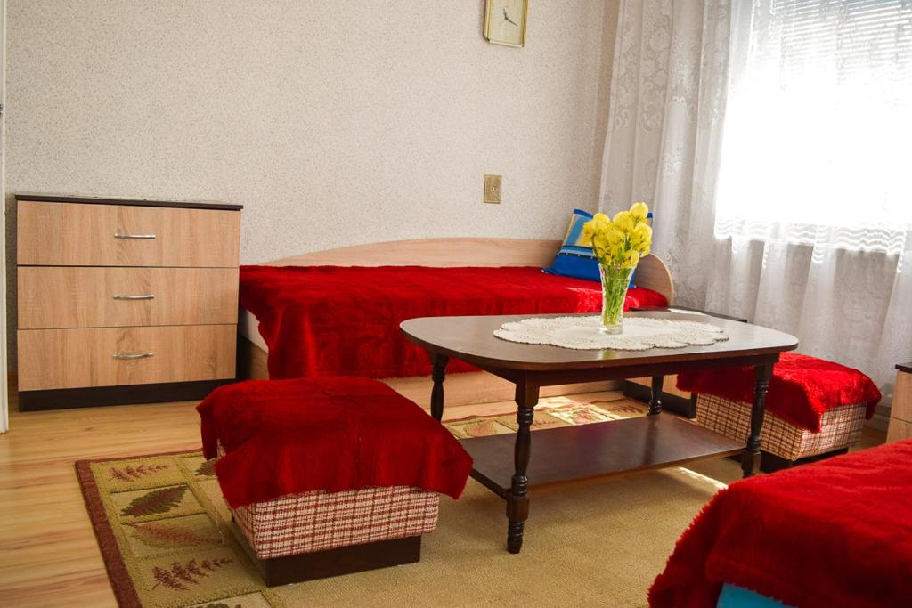 a room with a table and a bed with red sheets at Velkovski Guest House in Hisarya