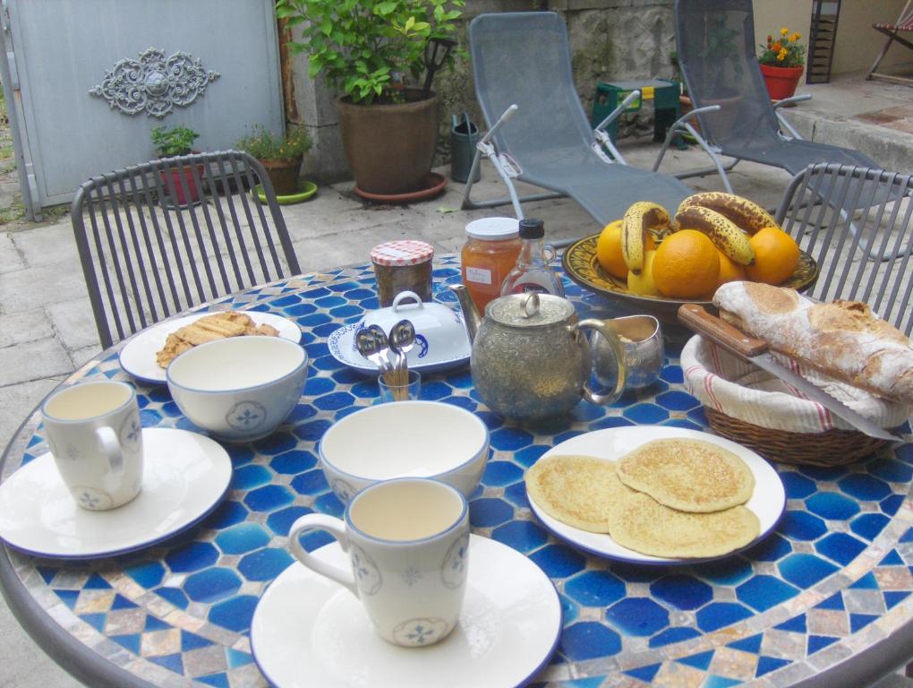 ein Tisch mit Tassen und Teller mit Essen drauf in der Unterkunft Le Patio Gironnais in Saint-Girons