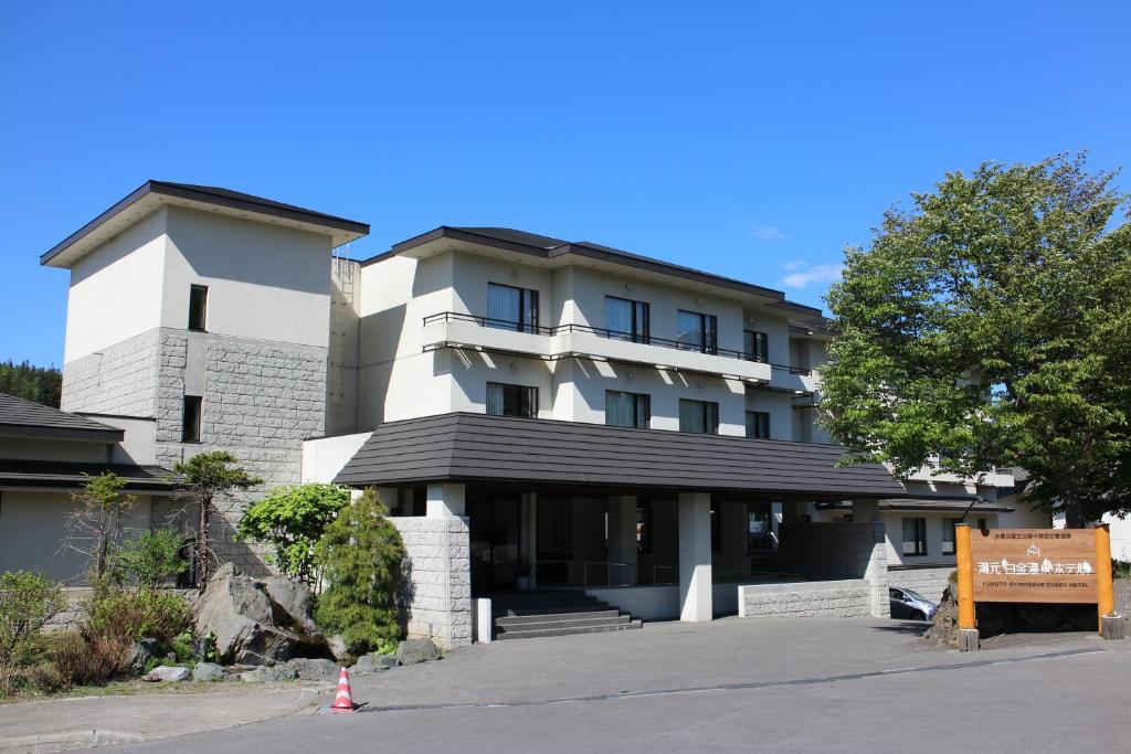 un edificio con una señal delante de él en Yumoto Shirogane-Onsen Hotel, en Biei