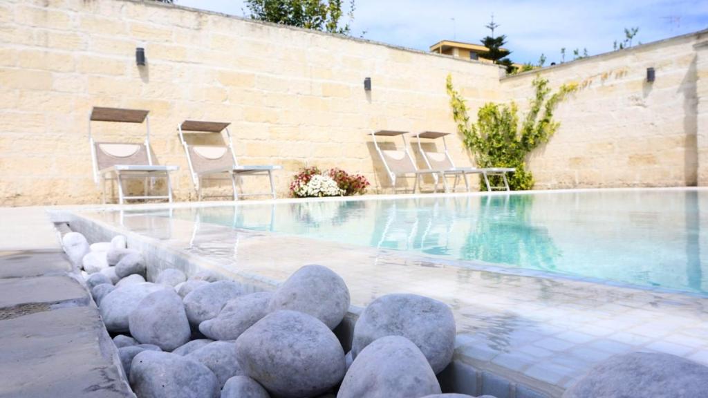 a swimming pool with chairs and rocks in the water at Palazzo Circolone in Poggiardo