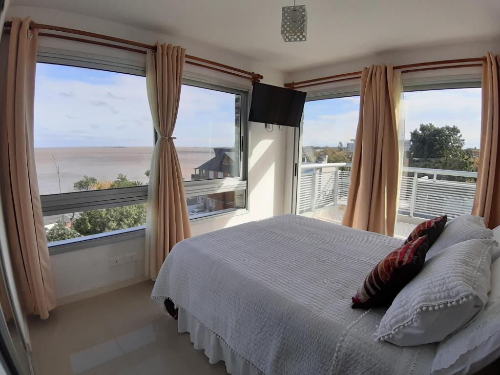 una camera con un letto e due grandi finestre di Eugenio Araus Apartamento 504 a Colonia del Sacramento