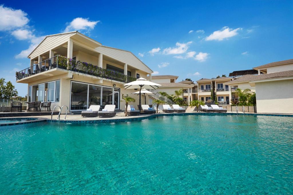 a swimming pool in front of a house at The Acacia Morjim in Morjim
