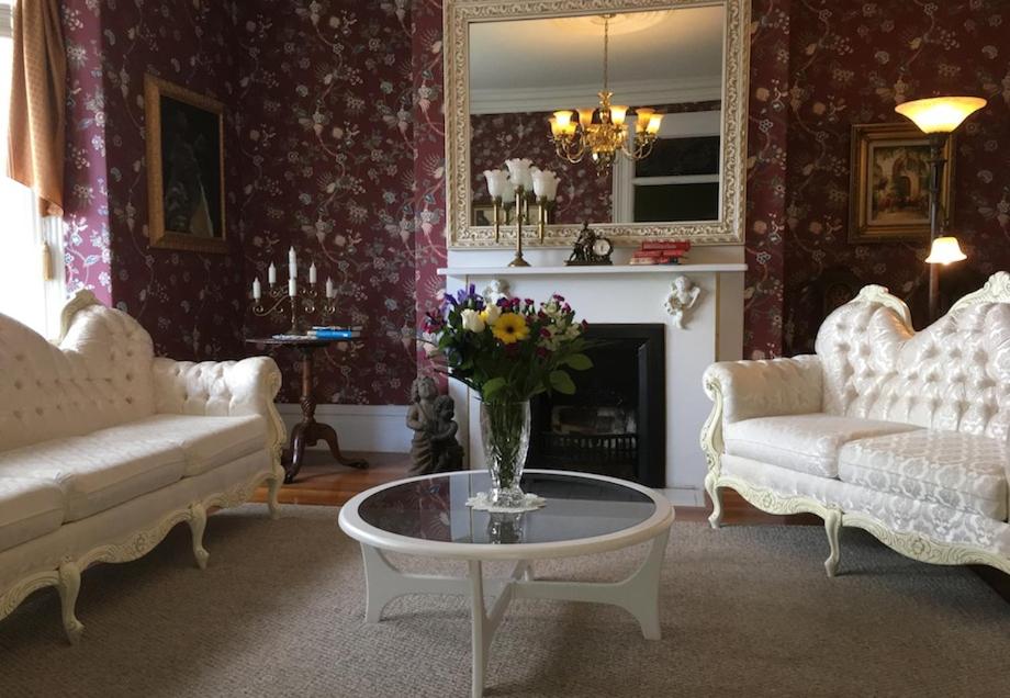 una sala de estar con 2 sofás blancos y una mesa con flores en Balmoral House Bed & Breakfast, en St. John's
