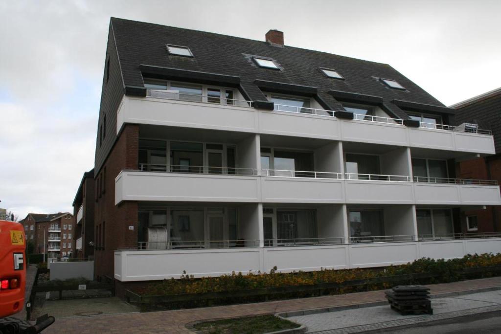 een groot wit gebouw met een zwart dak bij Schwalbe - Tripp in Westerland