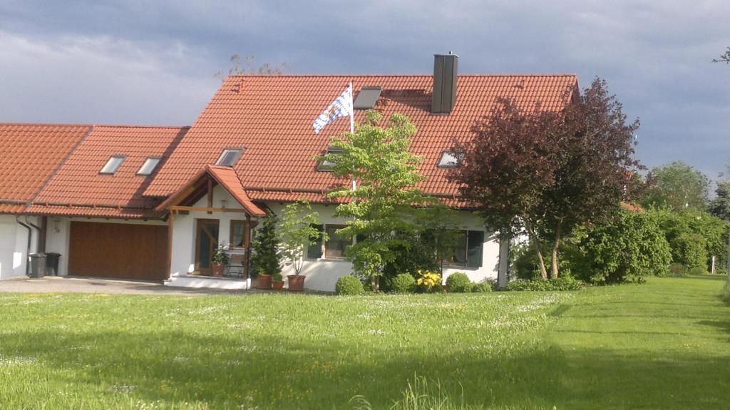 a house with a red roof and a yard at Ferienwohnung Wolfersdorf in Wolfersdorf