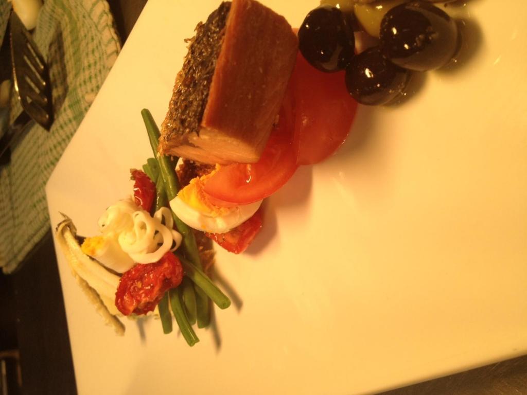 a white plate with a sandwich and vegetables on it at Sutherland House in Southwold