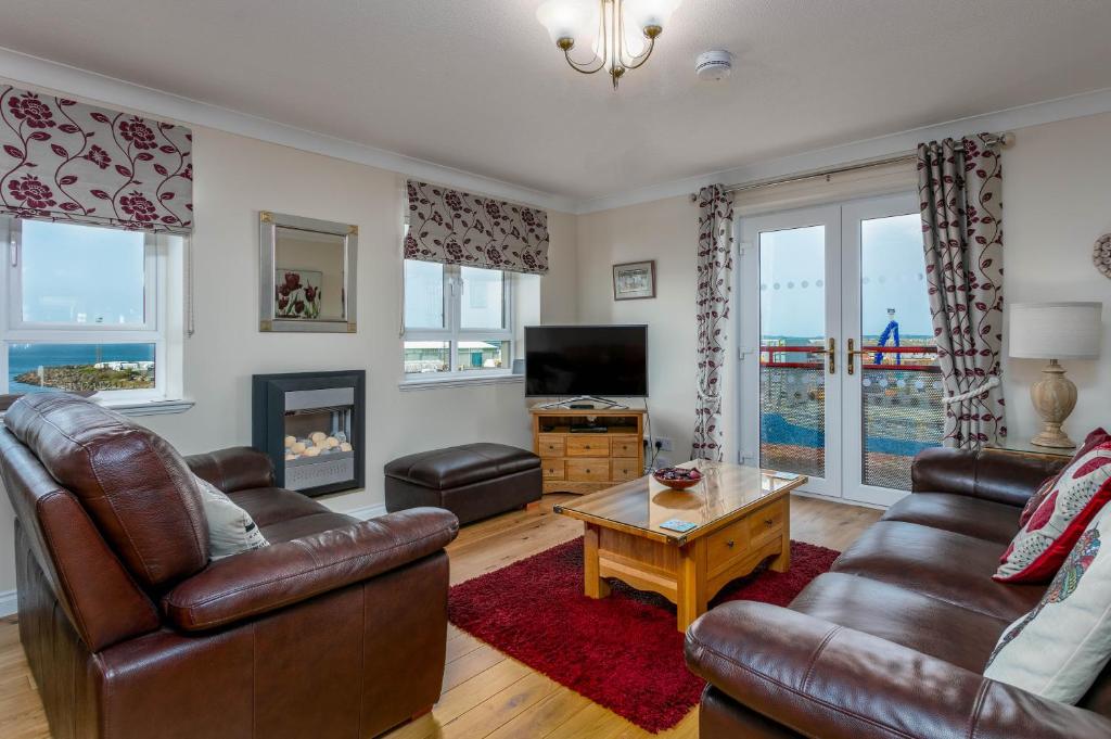 a living room with two leather couches and a fireplace at Arran View - Donnini Apartments in Ayr