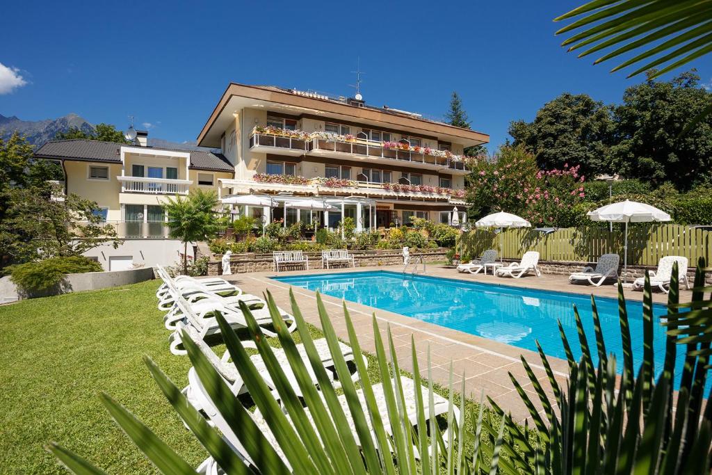 a hotel with a swimming pool and chairs and a building at Hotel Tiffany in Merano