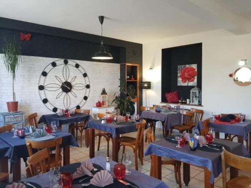 a restaurant with blue tables and chairs and a large wheel at le relais des forêts in Blessac
