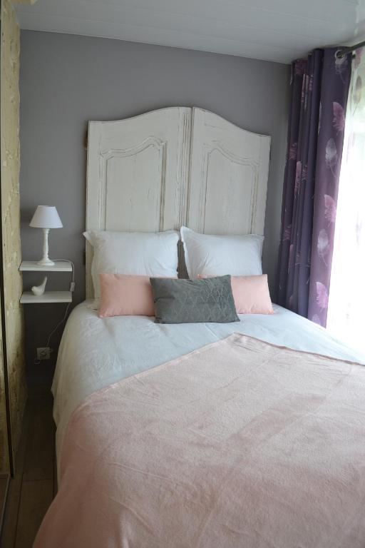 a bedroom with a large bed with pink pillows at L'instant Canal in Capestang