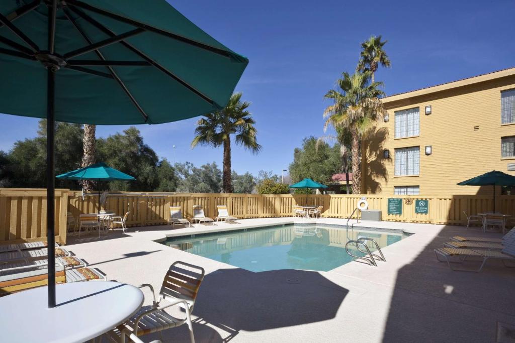 a pool with chairs and umbrellas next to a building at La Quinta Inn by Wyndham Phoenix Sky Harbor Airport in Tempe