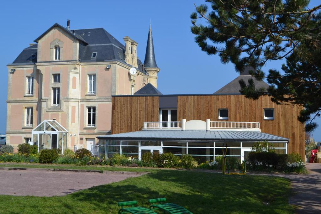 a large brick building with a spire on top of it at Les Tourelles Village de vacances in Asnelles