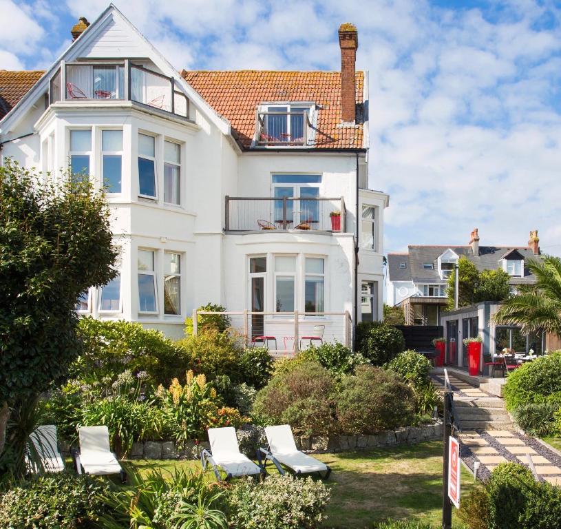 a white house with white chairs in front of it at Chelsea House in Falmouth