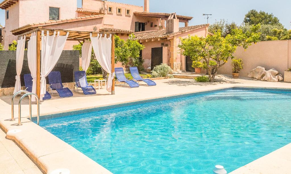 ソン・サルベーラにあるVilla Pula Viñas Country villa 3 bedrooms pool and fabulous views of the Pula golf course near Son serveraの青い椅子付きのスイミングプール、家