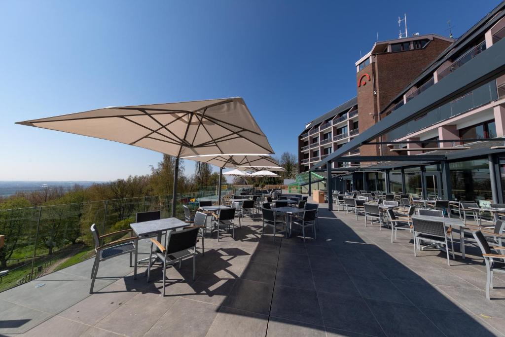 un patio con tavoli, sedie e ombrellone di Floreal Le Panoramique a Mont-Saint-Aubert