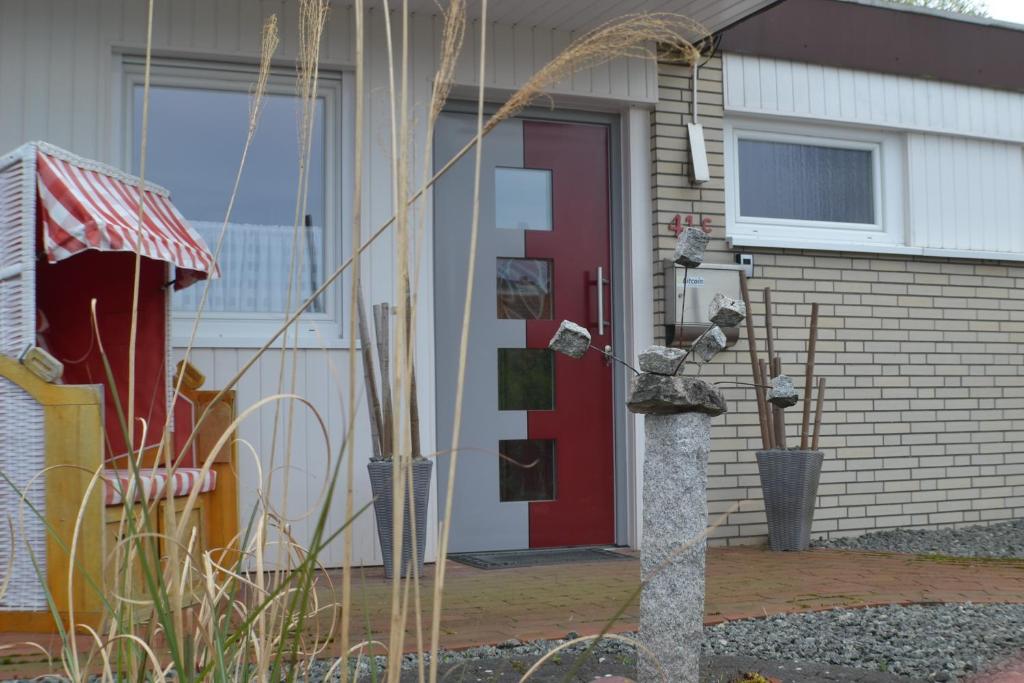 une maison avec une porte rouge et un système d'alimentation des oiseaux dans l'établissement Ferienhaus Bambus, mit Blick auf das Hooksieler Tief, à Horumersiel