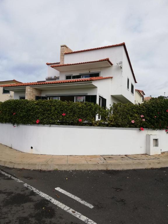 a white building with flowers on the side of a street at Moradia São Pedro in Porto Santo