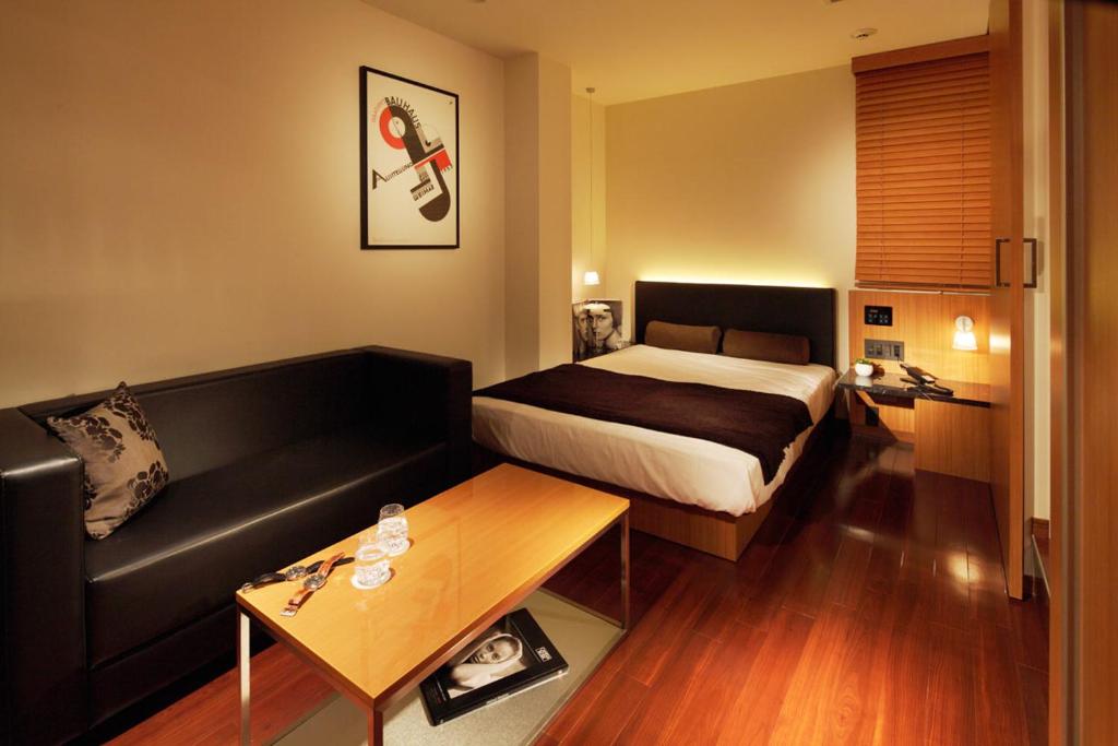 a hotel room with a bed and a couch at Hotel UNO Nishikawaguchi Nishiguchi in Kawaguchi