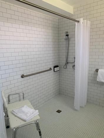 a bathroom with a shower with a chair in it at Sunset Inn in Islamorada