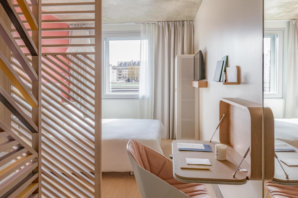 a room with a bed, desk and a window at OKKO Hotels Paris Gare de l'Est in Paris