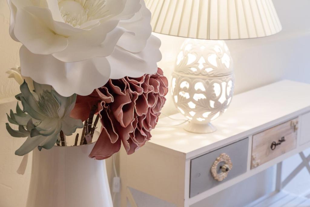 een tafel met een lamp en een vaas met bloemen bij Casa Anna by Home080 - Puglia Mia Apartments in Monopoli