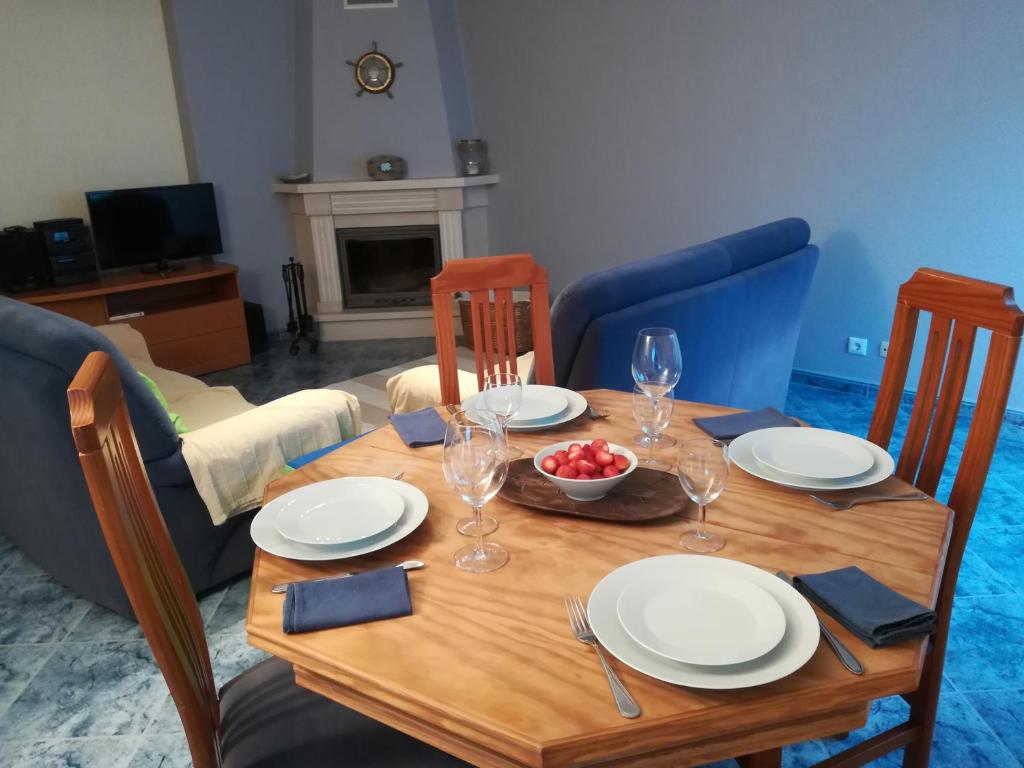 a wooden table with plates and a bowl of fruit on it at Casa de Férias Sesimbra in Sesimbra