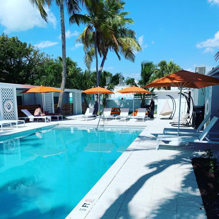 a swimming pool with orange umbrellas and chairs at Sunset Inn in Islamorada