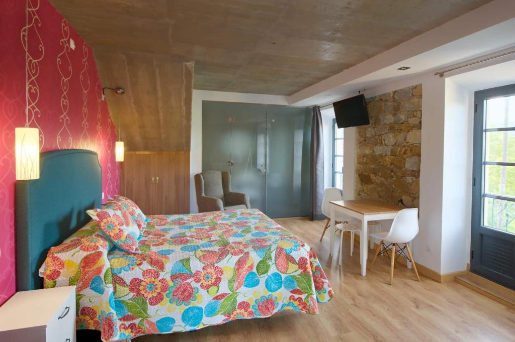 Un dormitorio con una cama con un edredón colorido y una mesa. en APARTAMENTOS LA LLONGAR en Infiesto