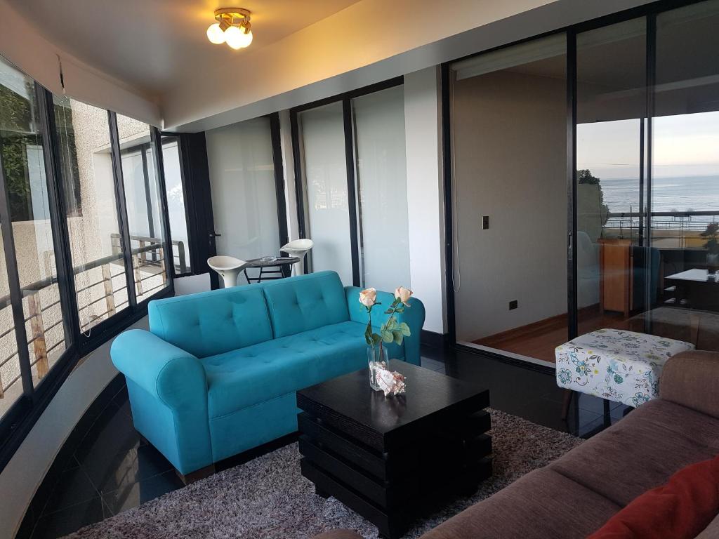 sala de estar con sofá azul y mesa en Departamento Reñaca, en Viña del Mar