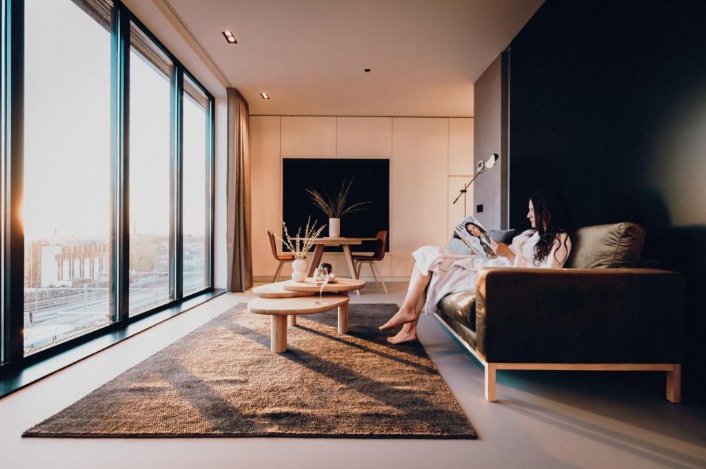 une femme assise sur un canapé dans un salon dans l'établissement CREATIVE VALLEY NEST – Luxury Rooftop Apartments, à Utrecht