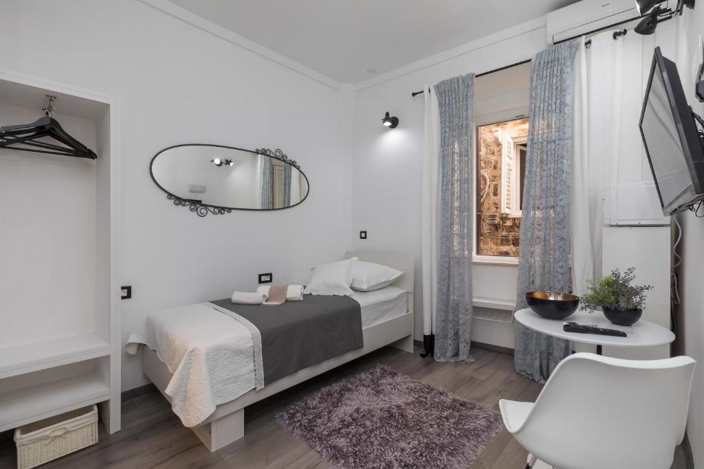 a white bedroom with a bed and a window at Guest House Tomasi One in Dubrovnik